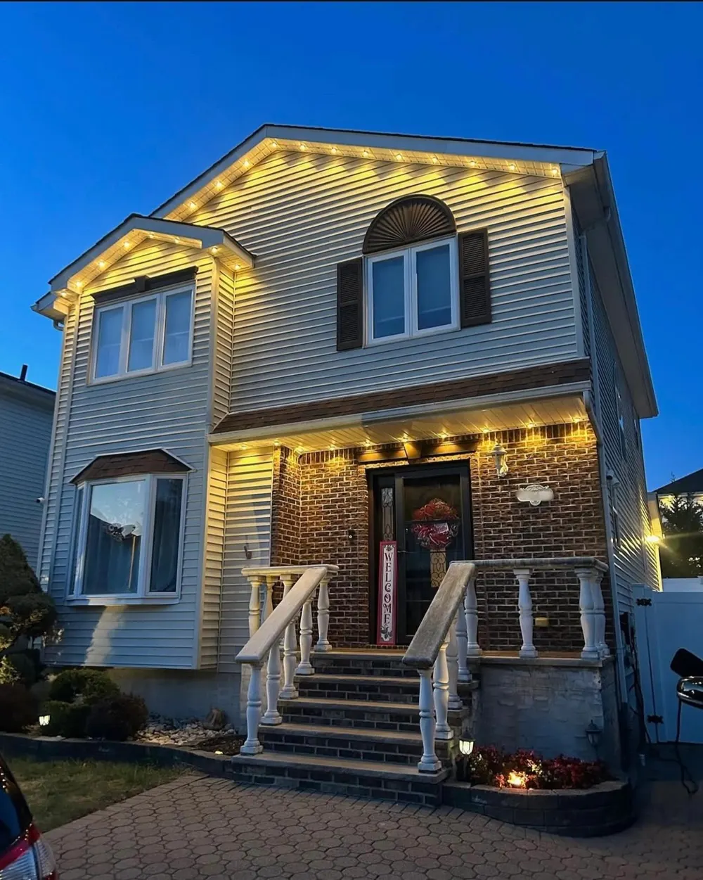 Two-story home lit at dusk by new exterior soffit lighting