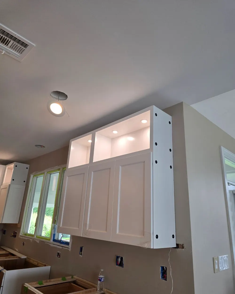 Kitchen remodel with lit glass-front cabinets and new recessed lighting