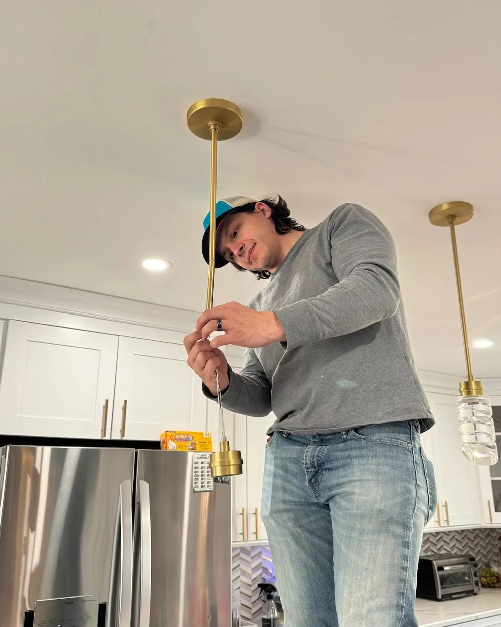 Covenant electrician installing brass pendant lights over a kitchen island